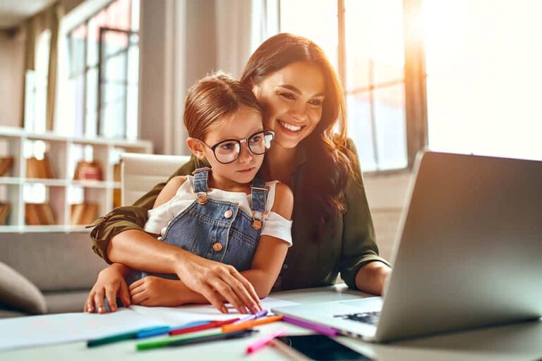 Business woman and mom working with her little daughter at a laptop. Freelance, work from home.