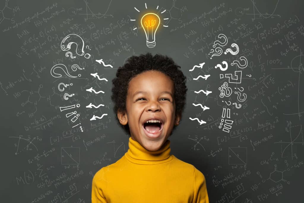 Smart black kid student with lightbulb on blackboard background. Brainstorming and idea concept