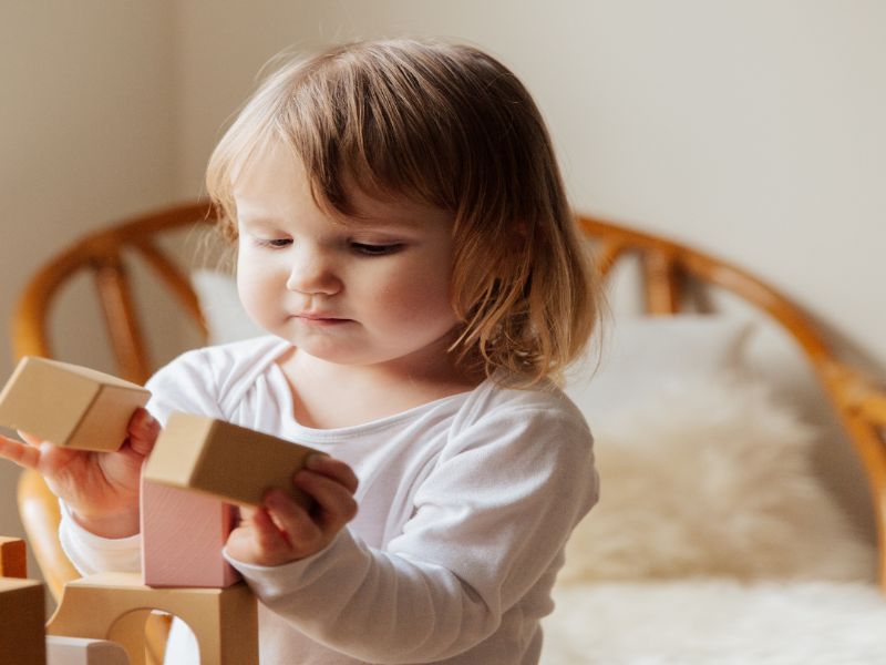 a little child playing wooden blocks