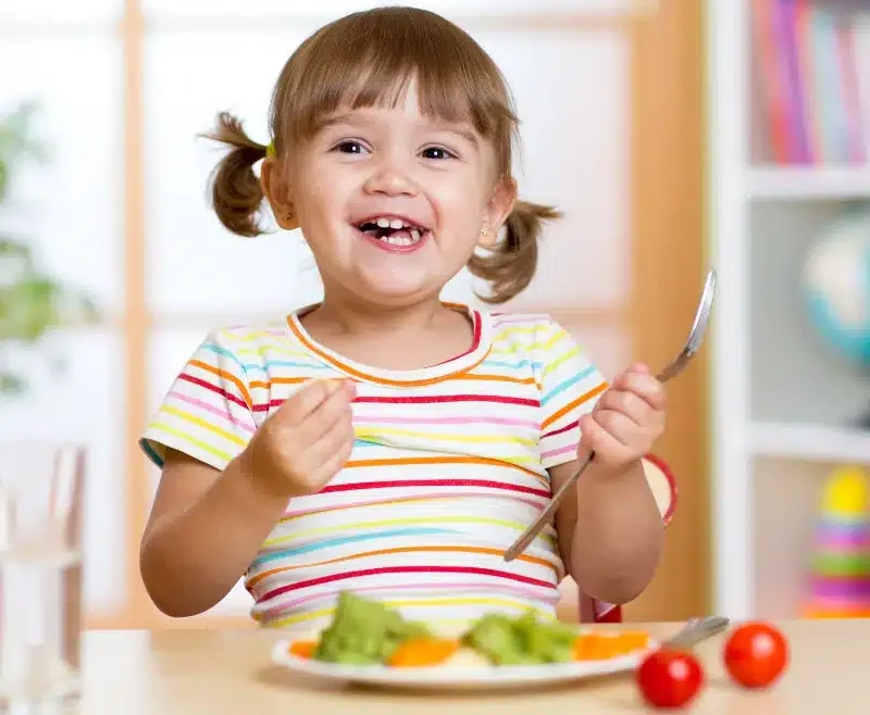 Happy child girl eating vegetables