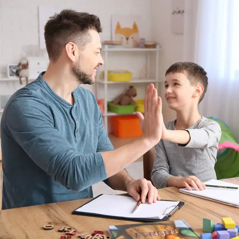 a child doing a high five to his therapist
