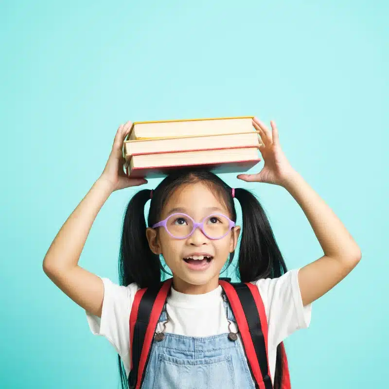 kid holding books above her head